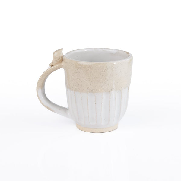 A handmade ceramic mug with a ribbed white lower half and a textured beige upper half, featuring a small decorative loop on the handle, set against a plain white background.